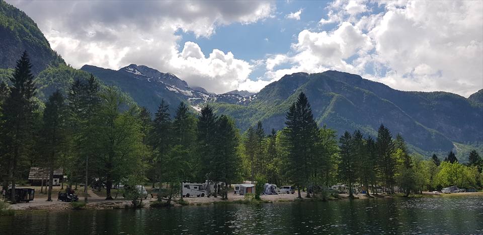 A lakeside hospitality site spread across open ground beneath forested alpine slopes.