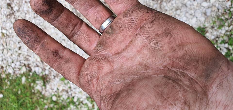 A dirt-marked hand during outdoor infrastructure work.