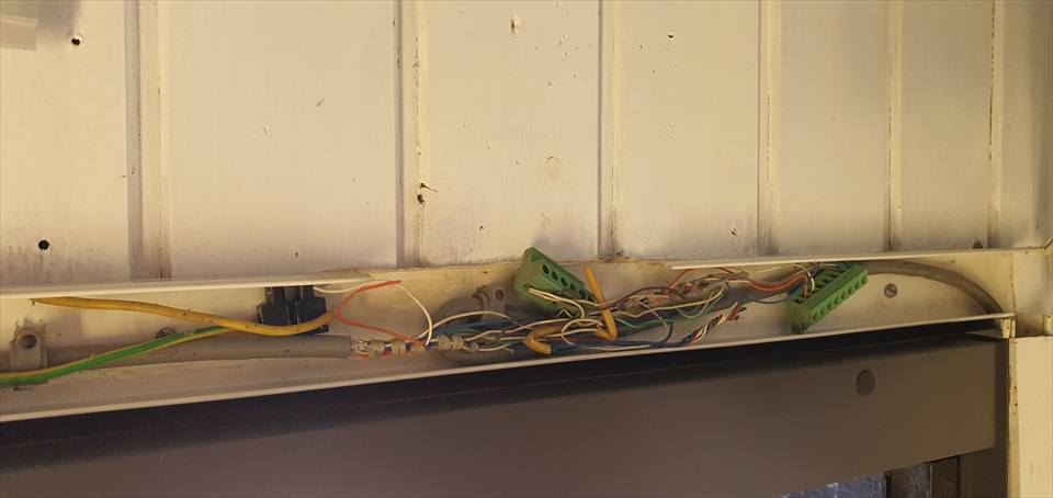 An opened service point showing inherited wiring and conduits before redesign work.